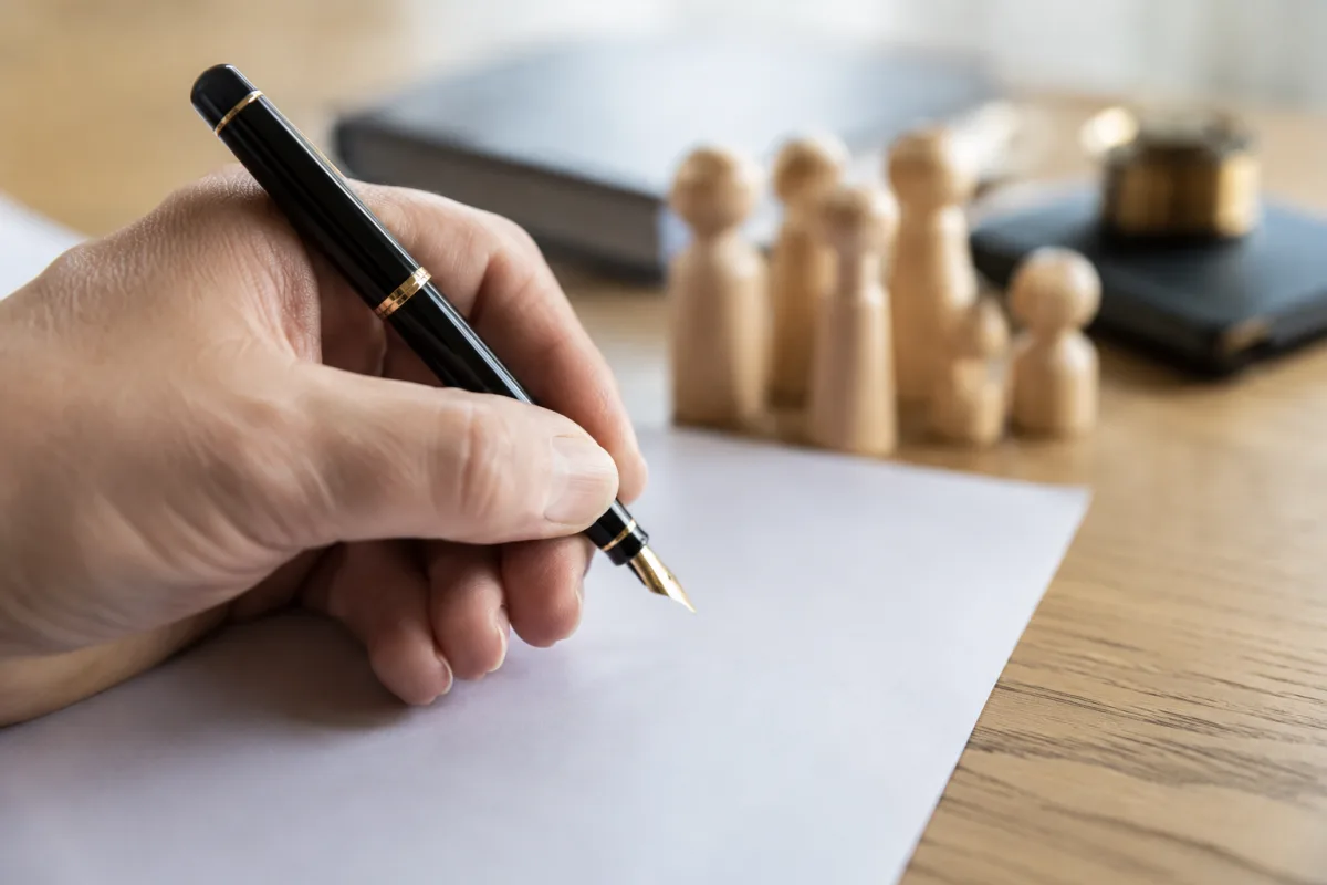 Main tenant un stylo plume au-dessus d'un document notarié de déclaration de succession