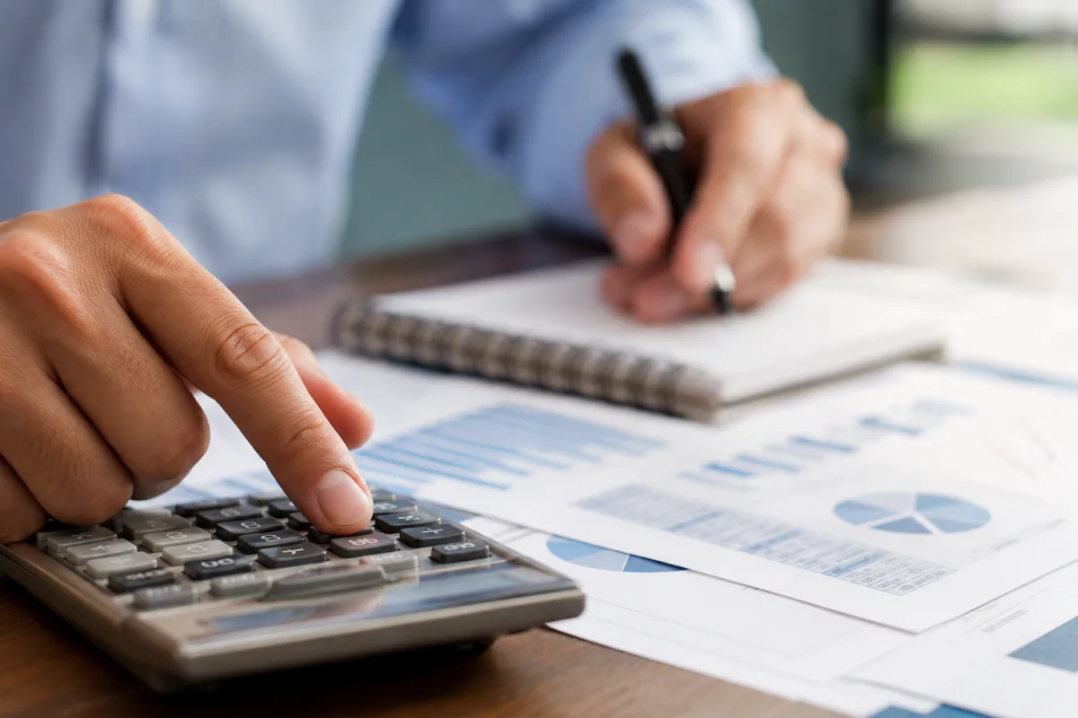 Gros plan sur les doigts d'un investisseur tapant des calculs sur une calculatrice de bureau professionnelle