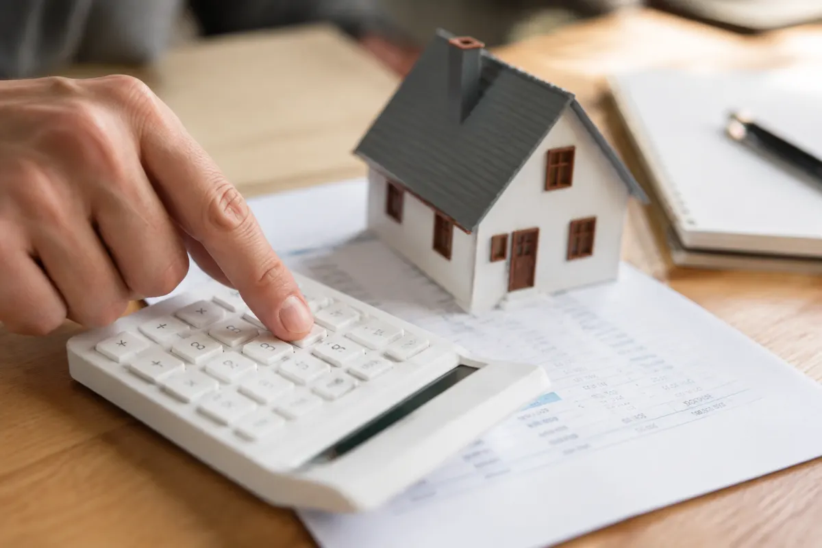Mon analyse sur le rachat de crédit pour propriétaire et ses pièges Gros plan sur un stylo signant un contrat de prêt bancaire posé sur une calculatrice