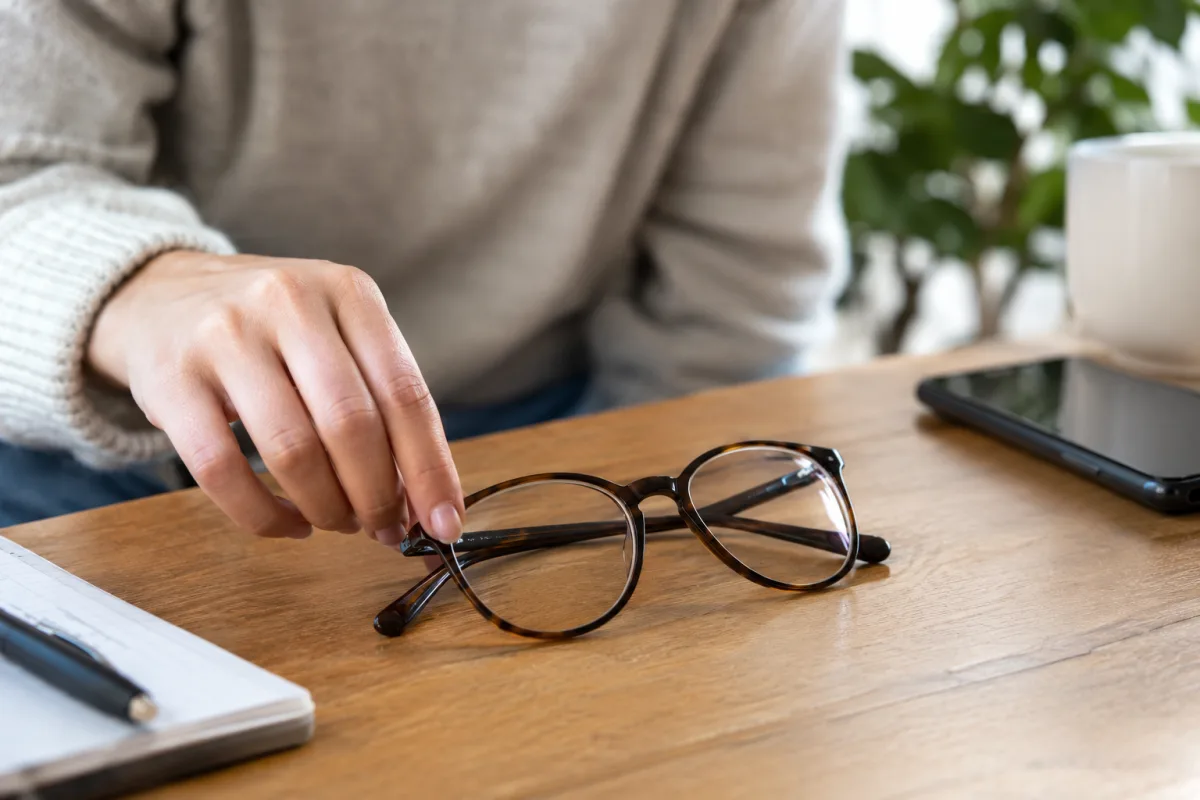 Gros plan sur une paire de montures de lunettes posée à côté d'un contrat d'assurance ouvert